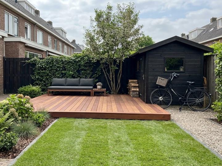 Impressie van een nieuwe hardhouten vlonder met loungebank naast een tuinhuis